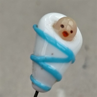 Gammel nipsenål med glas barn svøbt i hvidt klæde med en blå stribe.